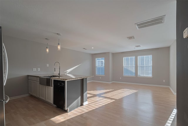 1101 Saulnier St, Houston, TX 77019 - kitchen featuring light wood-style floors, a peninsula, light stone countertops, black dishwasher, and hanging light fixtures