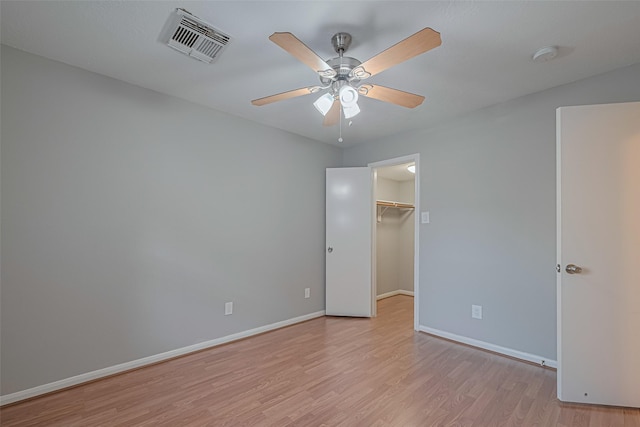 1101 Saulnier St, Houston, TX 77019 - unfurnished bedroom featuring light wood finished floors, a walk in closet, a closet, and ceiling fan