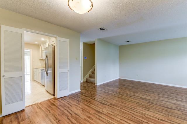 14436 Misty Meadow Ln, Houston, TX 77079 - empty room featuring light wood-style floors, stairway, and a textured ceiling