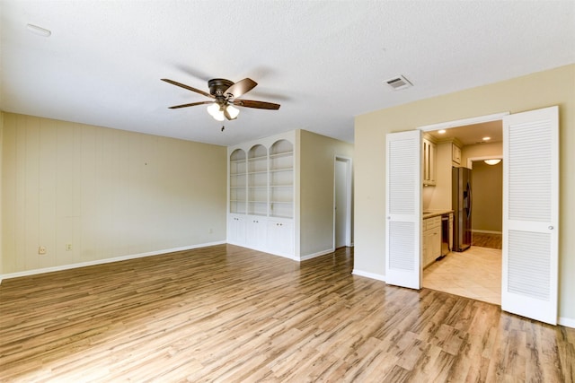 14436 Misty Meadow Ln, Houston, TX 77079 - unfurnished room featuring ceiling fan, light wood-style floors, a textured ceiling, and built in shelves