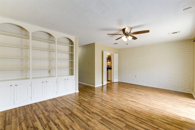 14436 Misty Meadow Ln, Houston, TX 77079 - unfurnished room featuring brick wall, wood finished floors, a ceiling fan, and a textured ceiling