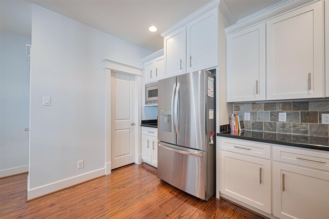 5307 Nett St Unit C, Houston, TX 77007 - kitchen featuring appliances with stainless steel finishes, light wood finished floors, white cabinetry, decorative backsplash, and recessed lighting