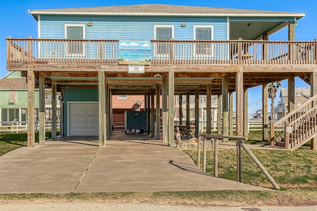 3401 Sand Castle Ln, Port Bolivar, TX 77650 - view of front of house featuring a carport, a garage, a wooden deck, stairway, and concrete driveway