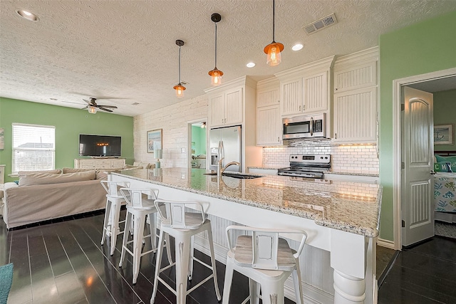 3401 Sand Castle Ln, Port Bolivar, TX 77650 - kitchen with appliances with stainless steel finishes, ceiling fan, open floor plan, a breakfast bar, and decorative backsplash