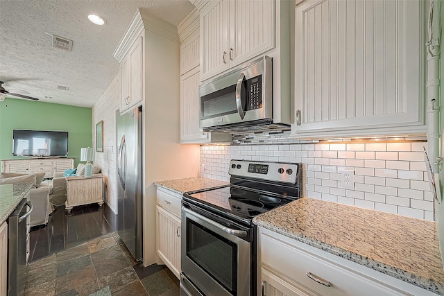 3401 Sand Castle Ln, Port Bolivar, TX 77650 - kitchen featuring stainless steel appliances, open floor plan, a textured ceiling, tasteful backsplash, and ceiling fan