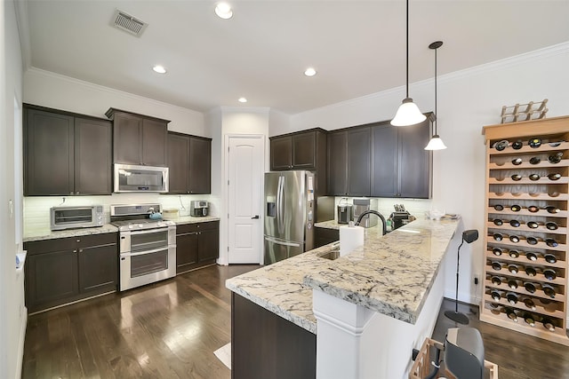 925 W 19th St Unit B, Houston, TX 77008 - kitchen featuring appliances with stainless steel finishes, a peninsula, a kitchen bar, ornamental molding, and dark brown cabinetry