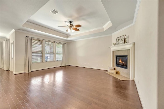 716 Saturnia Ln, League City, TX 77573 - unfurnished living room featuring a tray ceiling, a ceiling fan, ornamental molding, a fireplace, and wood finished floors