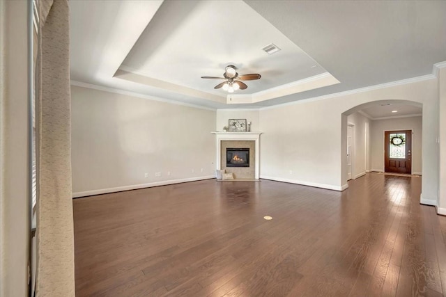 716 Saturnia Ln, League City, TX 77573 - unfurnished living room featuring a tray ceiling, a ceiling fan, dark wood-type flooring, arched walkways, and ornamental molding
