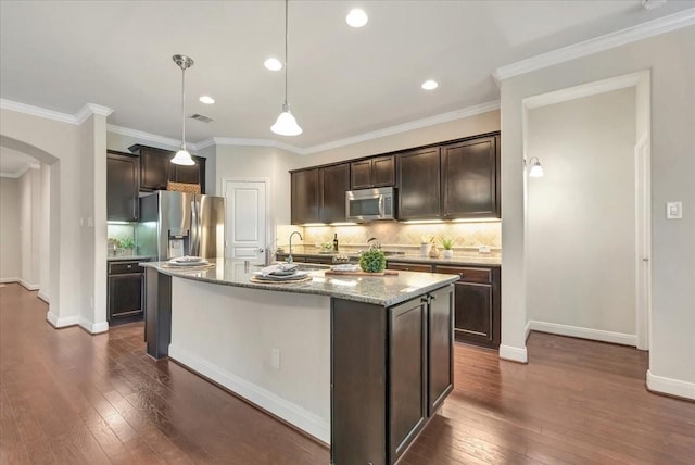 716 Saturnia Ln, League City, TX 77573 - kitchen with stainless steel appliances, arched walkways, dark brown cabinets, dark wood finished floors, and ornamental molding