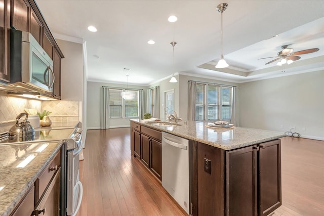 716 Saturnia Ln, League City, TX 77573 - kitchen featuring appliances with stainless steel finishes, crown molding, wood-type flooring, backsplash, and dark brown cabinetry