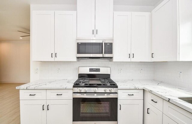 8310 Parnell St, Houston, TX 77051 - kitchen featuring stainless steel appliances, white cabinetry, backsplash, and light stone countertops