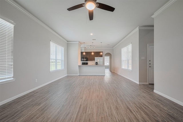 915 Lakeland Cir, Rosharon, TX 77583 - unfurnished living room featuring healthy amount of natural light, ceiling fan, ornamental molding, wood finished floors, and arched walkways