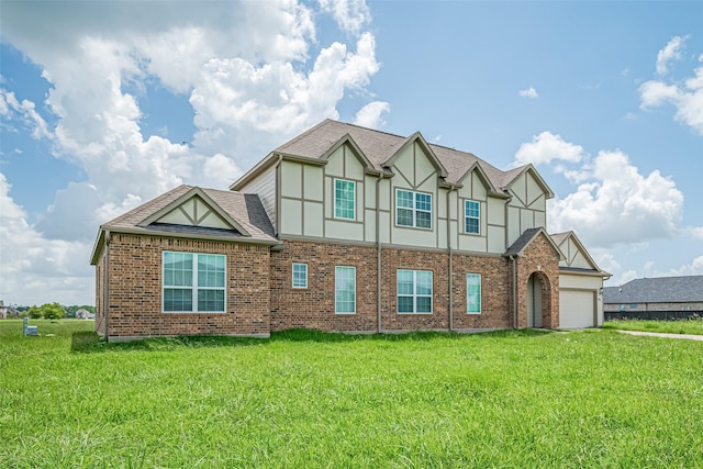 915 Lakeland Cir, Rosharon, TX 77583 - tudor house with stucco siding, an attached garage, a front yard, a shingled roof, and brick siding