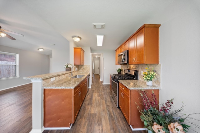 10335 Caribou Cv, Missouri City, TX 77459 - kitchen with appliances with stainless steel finishes, tasteful backsplash, a peninsula, dark wood finished floors, and light stone counters