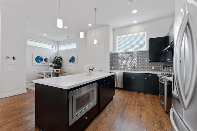 1211 Bonner St, Houston, TX 77007 - kitchen featuring appliances with stainless steel finishes, dark cabinets, under cabinet range hood, light countertops, and recessed lighting