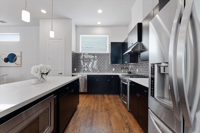 1211 Bonner St, Houston, TX 77007 - kitchen with appliances with stainless steel finishes, under cabinet range hood, light countertops, light wood-type flooring, and backsplash