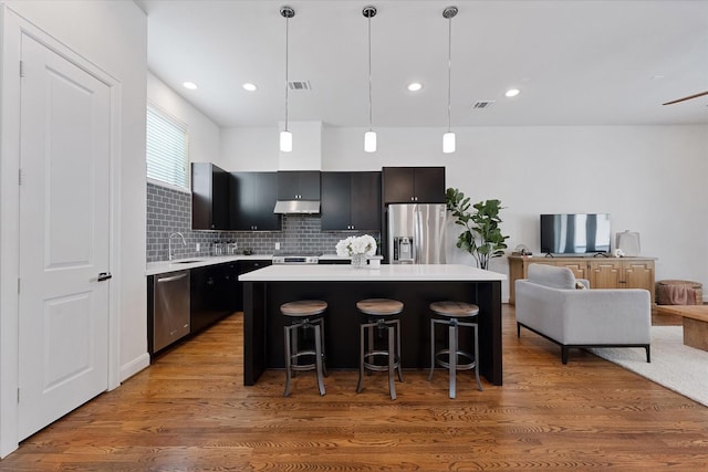 1211 Bonner St, Houston, TX 77007 - kitchen with stainless steel appliances, light countertops, under cabinet range hood, a center island, and a kitchen bar