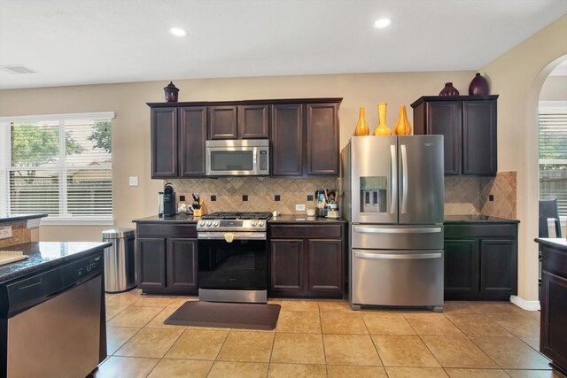3215 W Trail Dr, Pearland, TX 77584 - kitchen with appliances with stainless steel finishes, arched walkways, tasteful backsplash, dark countertops, and dark brown cabinetry