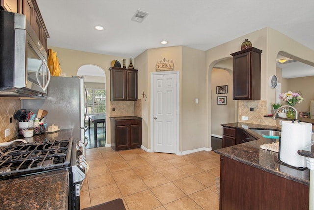 3215 W Trail Dr, Pearland, TX 77584 - kitchen featuring appliances with stainless steel finishes, arched walkways, tasteful backsplash, dark stone counters, and recessed lighting