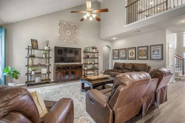 9227 Forest Creek Dr, Tomball, TX 77375 - living room with arched walkways, wood finished floors, ceiling fan, high vaulted ceiling, and stairs