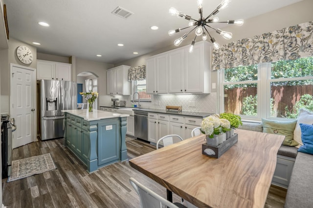9227 Forest Creek Dr, Tomball, TX 77375 - kitchen featuring appliances with stainless steel finishes, arched walkways, a chandelier, white cabinets, and dark wood finished floors