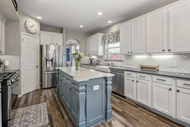 9227 Forest Creek Dr, Tomball, TX 77375 - kitchen featuring stainless steel appliances, arched walkways, white cabinets, a center island, and recessed lighting