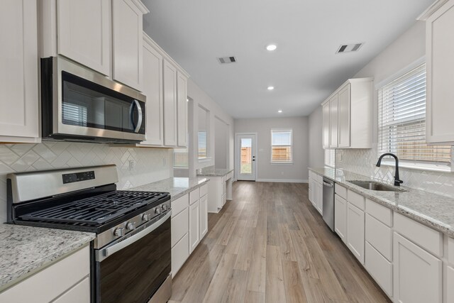 3122 Banyan Dr, Texas City, TX 77510 - kitchen with stainless steel appliances, light wood-type flooring, white cabinetry, tasteful backsplash, and recessed lighting