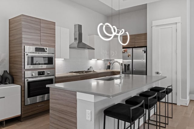 1617 Wheeler St Unit C, Houston, TX 77004 - kitchen featuring appliances with stainless steel finishes, wall chimney exhaust hood, modern cabinets, a breakfast bar, and light wood-type flooring