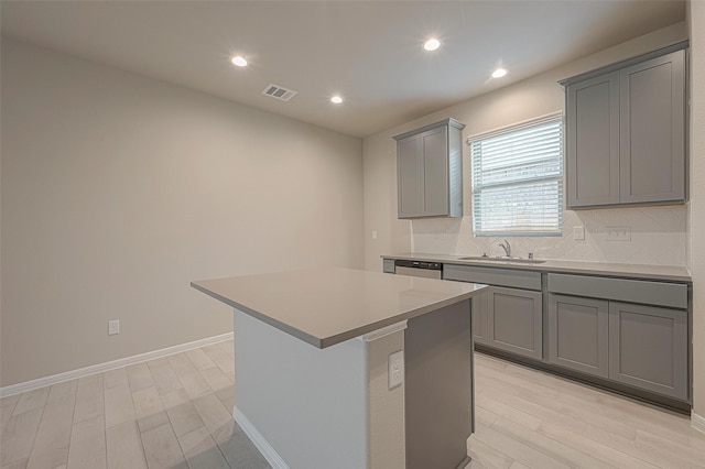 1452 Sundown Glen Ln, Katy, TX 77493 - kitchen featuring gray cabinets, light wood-style flooring, tasteful backsplash, a center island, and light countertops