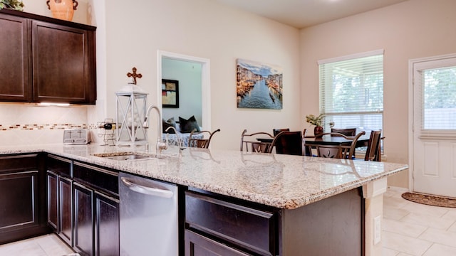 4407 Crosley Field Dr, Spring, TX 77389 - kitchen featuring dishwasher, light stone countertops, a peninsula, dark brown cabinetry, and light tile patterned flooring