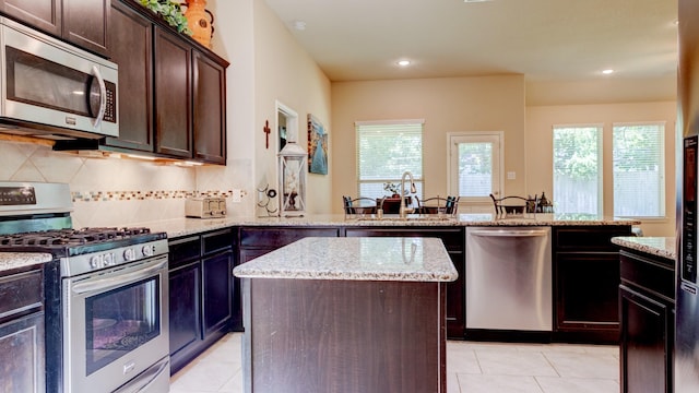 4407 Crosley Field Dr, Spring, TX 77389 - kitchen featuring stainless steel appliances, a peninsula, a kitchen island, decorative backsplash, and light tile patterned flooring