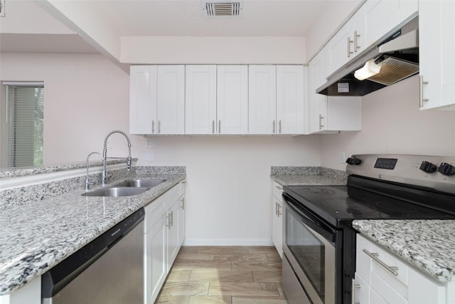 12606 Wellington Park Dr, Houston, TX 77072 - kitchen featuring appliances with stainless steel finishes, under cabinet range hood, light stone countertops, white cabinetry, and a peninsula