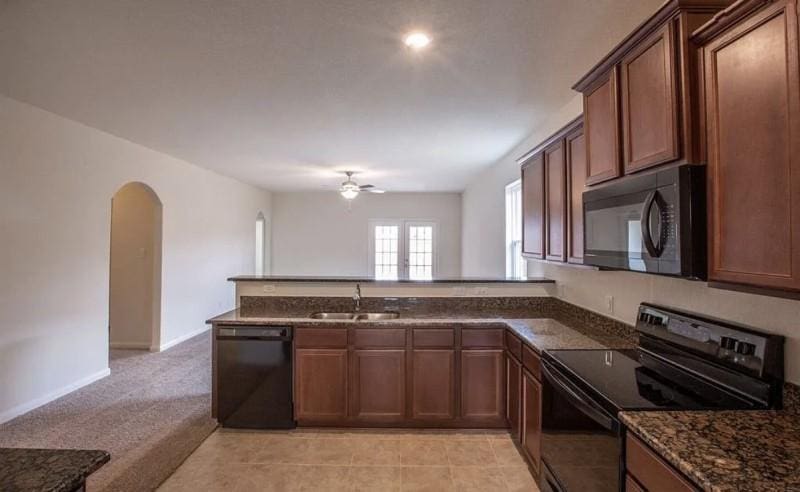 15302 Albert Oak Dr, Humble, TX 77396 - kitchen featuring black appliances, a peninsula, ceiling fan, arched walkways, and dark stone counters
