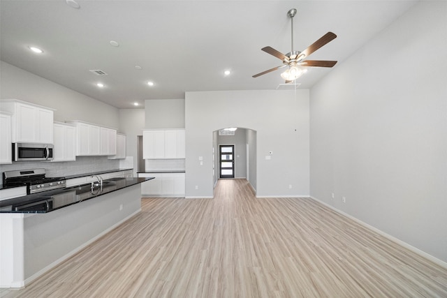 5319 Costa Ridge Ln, Katy, TX 77493 - kitchen with stainless steel appliances, arched walkways, high vaulted ceiling, dark countertops, and light wood-style floors