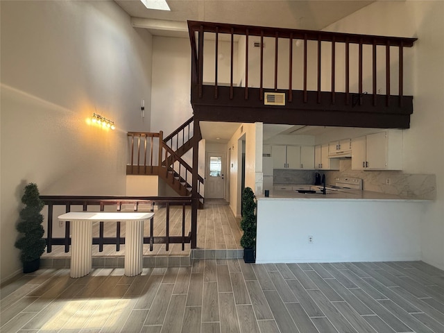 12922 Wirevine Ln, Houston, TX 77072 - kitchen featuring white appliances, a towering ceiling, wood finish floors, white cabinets, and light countertops