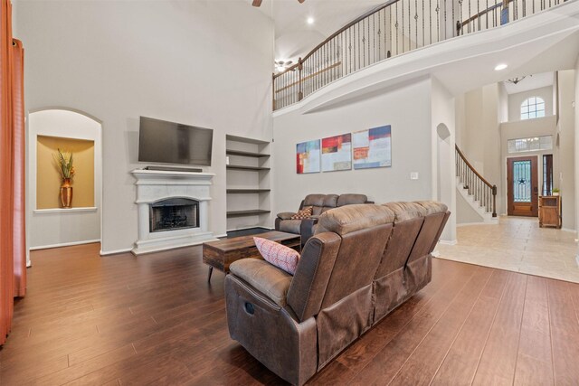 4314 Walden Terrace Ln, Humble, TX 77396 - living room with a high ceiling, dark wood-type flooring, built in features, stairway, and a fireplace with raised hearth