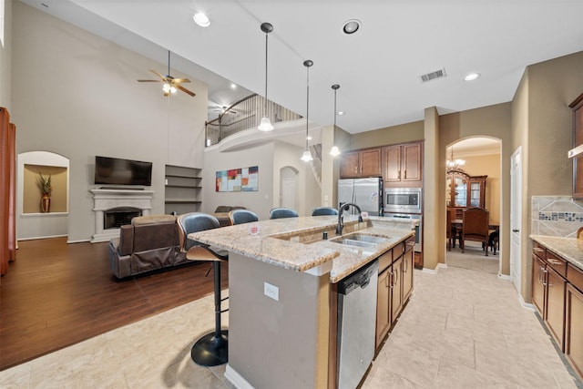 4314 Walden Terrace Ln, Humble, TX 77396 - kitchen featuring stainless steel appliances, arched walkways, a kitchen breakfast bar, brown cabinets, and a high ceiling