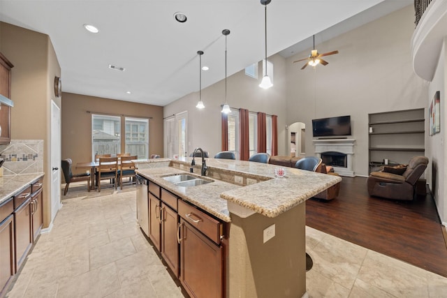 4314 Walden Terrace Ln, Humble, TX 77396 - kitchen with a center island with sink, pendant lighting, ceiling fan, brown cabinets, and a fireplace