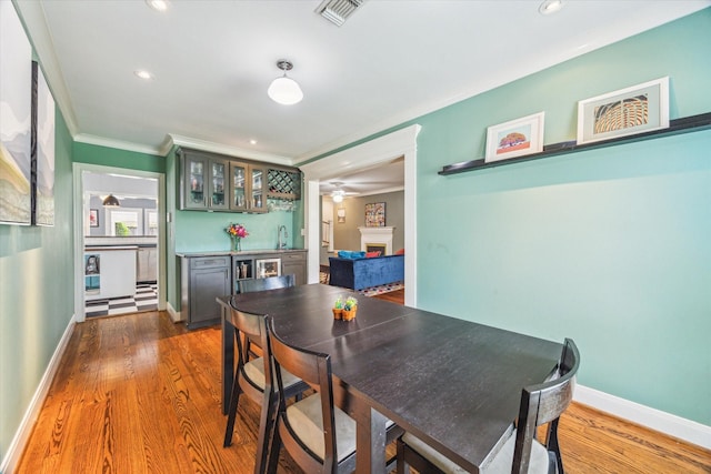308 W 33rd St, Houston, TX 77018 - dining space featuring a dry bar, a fireplace, recessed lighting, wood finished floors, and crown molding