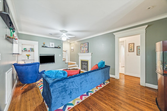 308 W 33rd St, Houston, TX 77018 - living room featuring a fireplace, wood finished floors, a ceiling fan, and ornamental molding