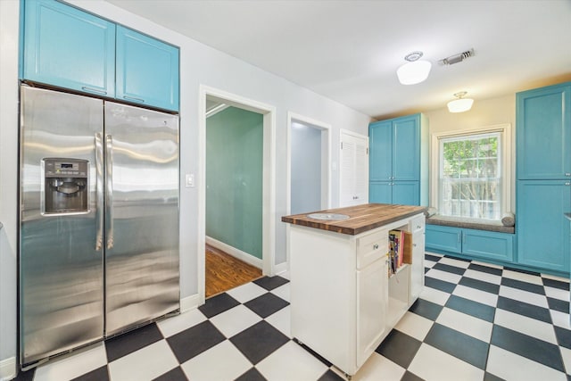 308 W 33rd St, Houston, TX 77018 - kitchen with high end fridge, light flooring, blue cabinetry, and butcher block countertops
