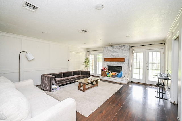11811 Braesridge Dr, Houston, TX 77071 - living room featuring french doors, a decorative wall, dark wood-style flooring, a textured ceiling, and a brick fireplace