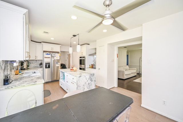11811 Braesridge Dr, Houston, TX 77071 - kitchen with appliances with stainless steel finishes, a kitchen island, light wood-type flooring, white cabinetry, and recessed lighting