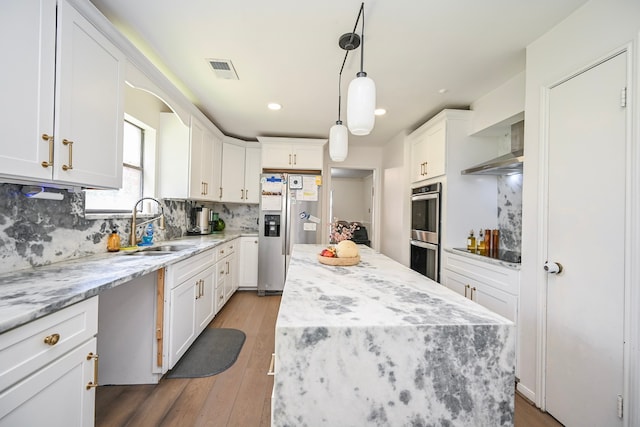 11811 Braesridge Dr, Houston, TX 77071 - kitchen featuring stainless steel appliances, wall chimney range hood, white cabinetry, a center island, and backsplash