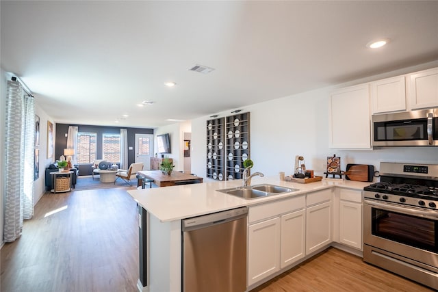 1603 Winwood Dr, Conroe, TX 77303 - kitchen featuring appliances with stainless steel finishes, a peninsula, open floor plan, light countertops, and white cabinetry