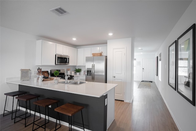 1603 Winwood Dr, Conroe, TX 77303 - kitchen with appliances with stainless steel finishes, a peninsula, a kitchen bar, light countertops, and white cabinets