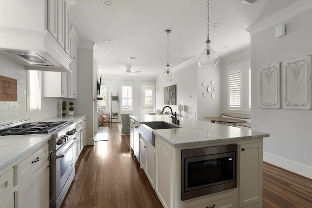 339 W 23rd St Unit A, Houston, TX 77008 - kitchen with stainless steel appliances, dark wood finished floors, a center island with sink, white cabinets, and ornamental molding