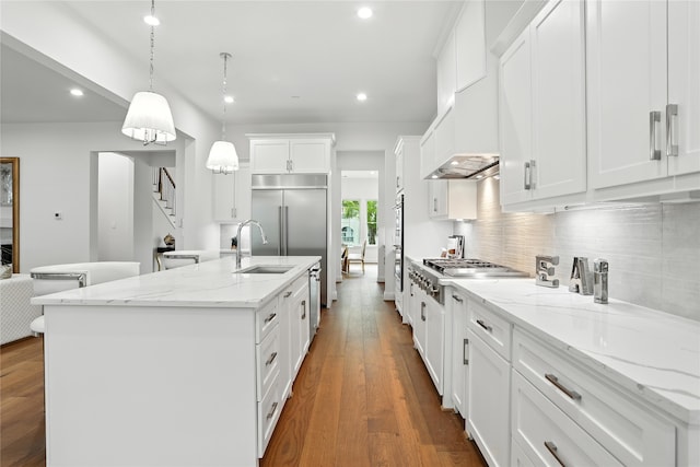 4951 Glenmeadow Dr, Houston, TX 77096 - kitchen featuring appliances with stainless steel finishes, backsplash, a center island with sink, recessed lighting, and white cabinetry