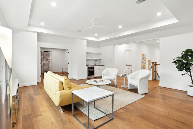 4951 Glenmeadow Dr, Houston, TX 77096 - living area with beverage cooler, a raised ceiling, bar with sink, recessed lighting, and light wood-style floors
