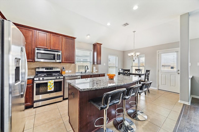6910 Lamar Park Ln, Houston, TX 77049 - kitchen featuring appliances with stainless steel finishes, lofted ceiling, a center island, a chandelier, and light tile patterned flooring